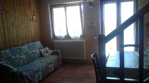 a living room with a couch and two windows at Holiday home Désirée in Sorico