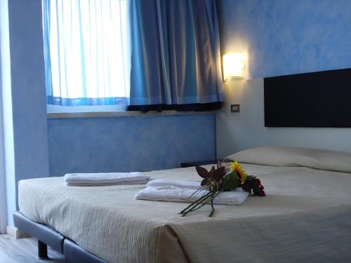 a bedroom with two beds with towels and a bouquet of flowers at Taki Village in Brenzone sul Garda