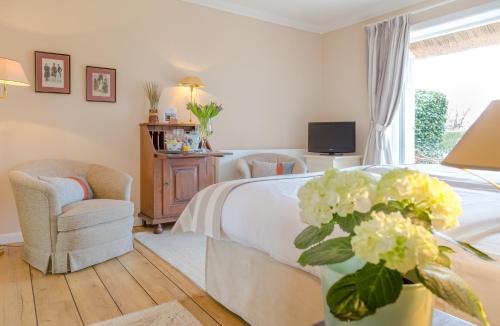 a bedroom with a bed and a tv and flowers at Boutiquehotel Seiler Hof Keitum in Keitum