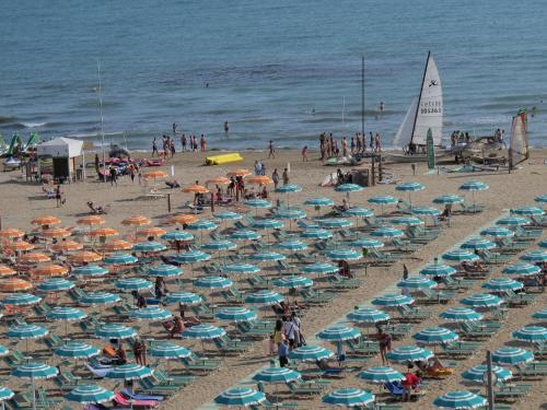 a beach filled with lots of blue and white umbrellas at Hotel Gaby in Rimini