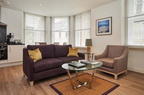 Braid Apartments by Mansley في إدنبرة: غرفة معيشة مع أريكة وطاولة وكراسي