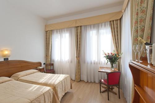a hotel room with two beds and a window at Hotel Cristallo in Venice-Lido