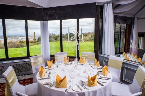 a dining room with a white table with chairs and windows at Best Western Frodsham Forest Hills Hotel in Frodsham