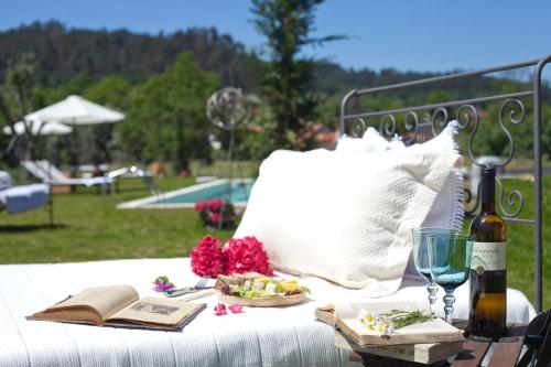 a picnic table with a bottle of wine and a plate of food at Carmo's Boutique Hotel - Small Luxury Hotels of the World in Ponte de Lima
