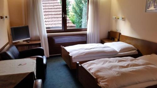 a hotel room with two beds and a window at Pension Laas in Ostfildern