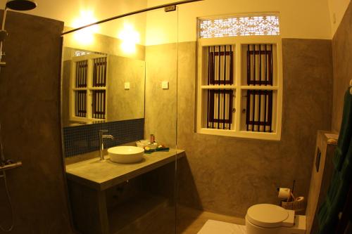 La salle de bains est pourvue d'un lavabo, de toilettes et d'un miroir. dans l'établissement Oasis Ayurveda Beach Hotel, à Ambalangoda