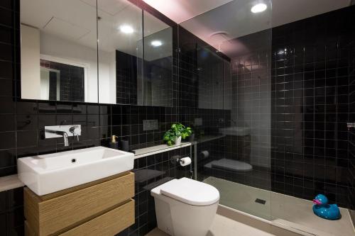 Beach Apartment Port Melbourne في ملبورن: حمام مع حوض ومرحاض ومرآة