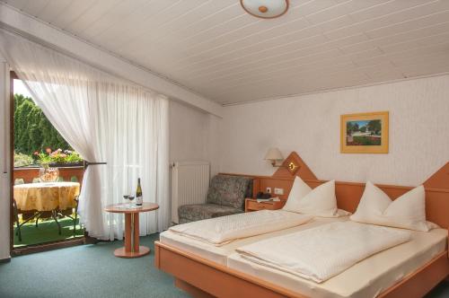 ein Schlafzimmer mit einem Bett, einem Stuhl und einem Tisch in der Unterkunft Gästehaus Hanewald in Bad Dürkheim