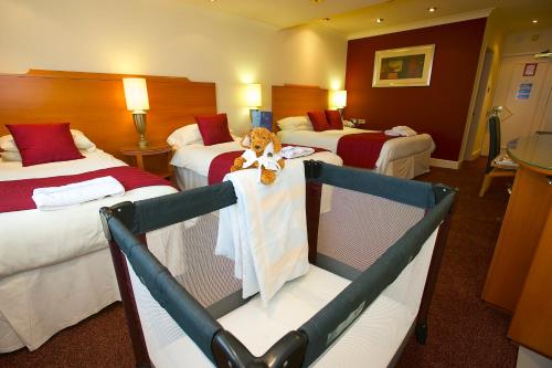 a hotel room with two beds with a teddy bear sitting on a table at Best Western Frodsham Forest Hills Hotel in Frodsham