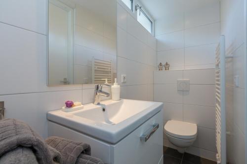 a white bathroom with a sink and a toilet at Apartments Valkenisse in Biggekerke