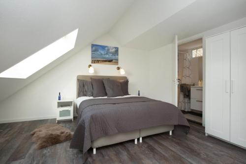 um quarto branco com uma cama e pisos em madeira em Apartments Valkenisse em Biggekerke