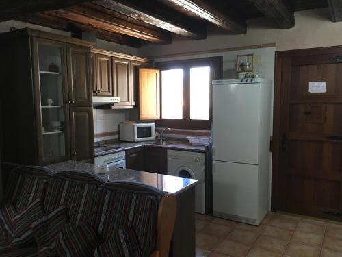 a kitchen with a white refrigerator and a table at El Pajar del Castillo in Mora de Rubielos