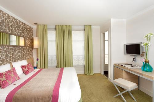 sypialnia z łóżkiem i biurkiem z telewizorem w obiekcie Le Marceau Bastille w Paryżu