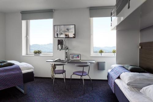 a bedroom with two beds and a desk and two chairs at Hotel Cabinn Vejle in Vejle