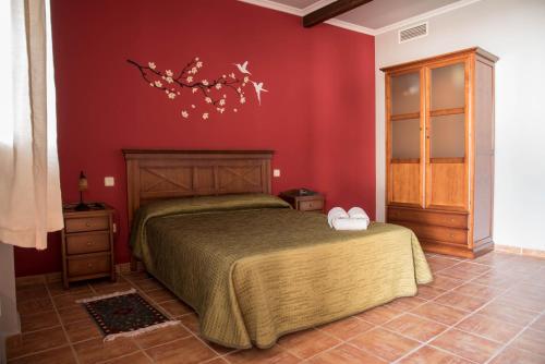 La SolanaにあるHotel Rural El Lagarの赤い壁のベッドルーム1室(ベッド1台付)