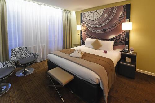 a hotel room with a large bed and a chair at Mercure Lyon Centre Beaux-Arts in Lyon