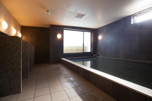 een grote badkamer met een hot tub en een raam bij Hotel Showmeikan in Mishima