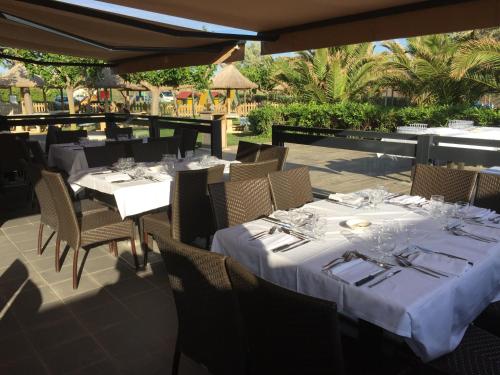 a restaurant with white tables and chairs on a patio at Hôtel Club la Font des Horts in Hyères