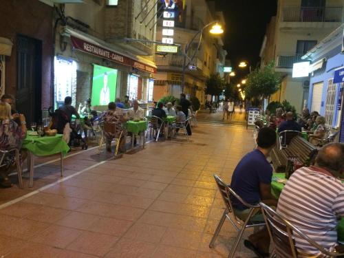 a group of people sitting at tables on a street at night at Hotel Madrid in Santiago de la Ribera