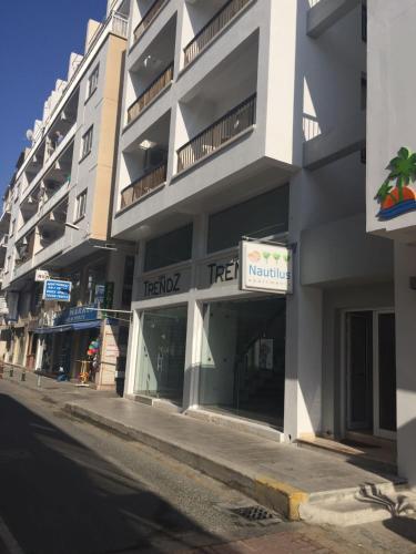 a tall white building with a tree sign on it at Nautilus Tourist Apartments in Larnaca