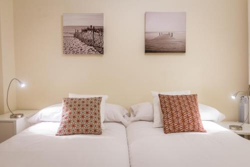 a white bed with two pillows on top of it at Apartamento Urumea in Donostia-San Sebastián