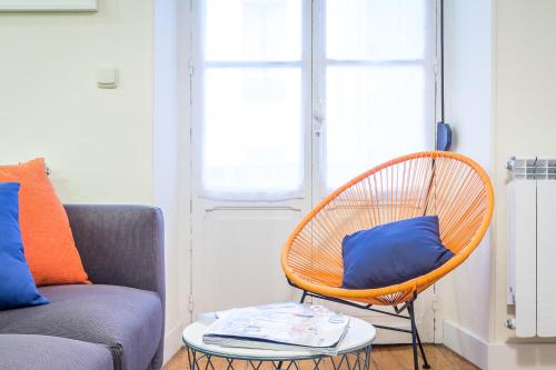 a rattan chair with a blue pillow sitting next to a couch at Apartamento Urumea in Donostia-San Sebastián