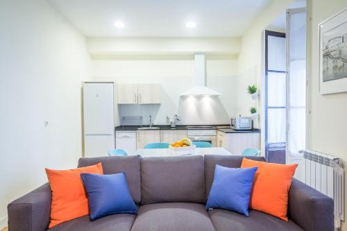 a living room with a couch with orange and blue pillows at Apartamento Urumea in Donostia-San Sebastián