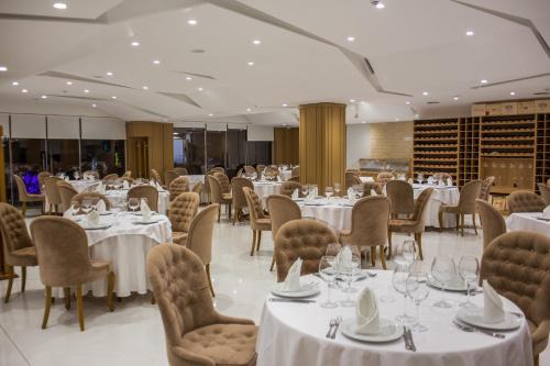 una sala da pranzo con tavoli, sedie e una tavola di Santa Quaranta Premium Resort a Sarandë