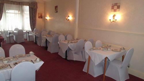 a dining room with white tables and white chairs at Tulip Hotel Blackpool in Blackpool