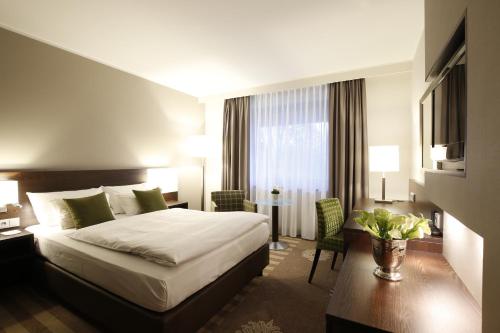 um quarto de hotel com uma cama, uma secretária e uma cadeira em Parkhotel Wittekindshof em Dortmund