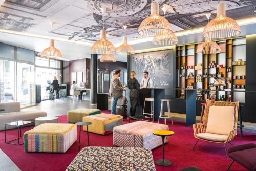 a lobby of a hotel with people standing at a counter at Novotel Lille Centre Gares in Lille
