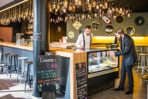 two men standing at a counter in a bar at Novotel Lille Centre Gares in Lille