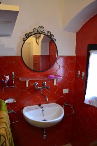 un bagno rosso con lavandino e specchio di Casa del Popolo 3 a Castagneto Carducci