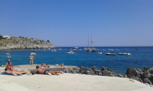 people laying on the beach with boats in the water at Bed & Breakfast Acquamarina in Castro di Lecce