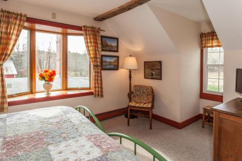 um quarto com uma cama, uma cadeira e janelas em Inn at Buck Hollow Farm em Fairfax