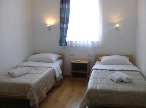 two beds in a small room with a window at Pansion Maglica in Međugorje