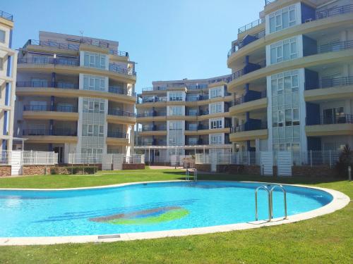 a swimming pool in front of some apartment buildings at Apartamento Piscina Playa Cedeira in Cedeira