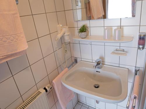 a white bathroom with a sink and a mirror at Landgasthof Adler in Utzmemmingen
