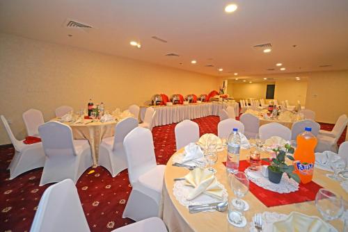 a banquet hall with white tables and white chairs at Alain Hotel Ajman in Ajman 