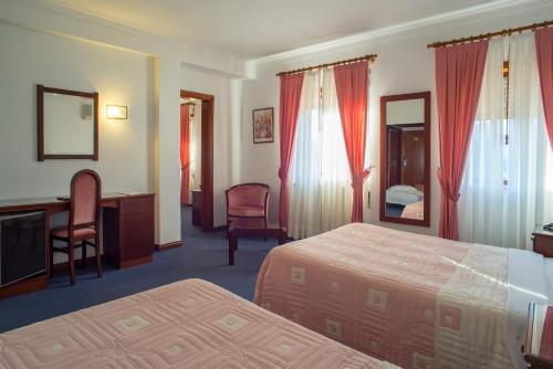 ein Hotelzimmer mit 2 Betten und einem Schreibtisch in der Unterkunft Hotel Boavista I in Melgaço