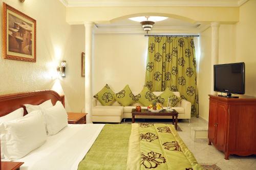 a bedroom with a bed and a tv and a couch at Zalagh Parc Palace in Fès