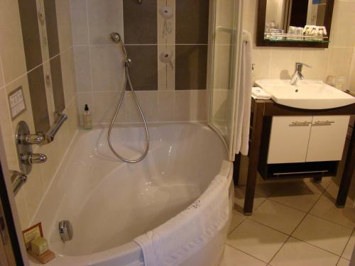 a bathroom with a tub and a sink at Hôtel Le Manoir aux Vaches in Yvetot