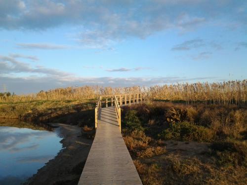 a wooden bridge over a river in a field at Hotel I Colori in SantʼAntìoco
