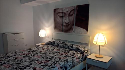 a bedroom with a bed with two lamps and a painting at loft con terraza y barbacoa in Lumpiaque