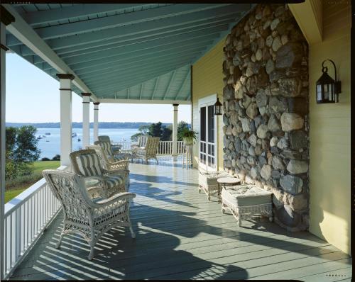 a porch with rocking chairs and a stone wall at Chebeague Island Inn in Royal Junction