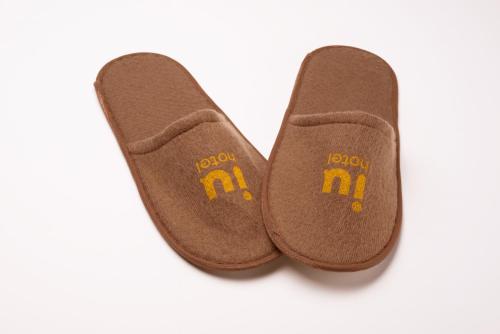 a pair of brown slippers with the m on them at IU Hotel Norh Guiyang Century City Convention Center in Guiyang