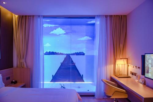 a bedroom with a bed and a desk and a window at IU Hotel Xian Zhonggulou Square in Xi'an