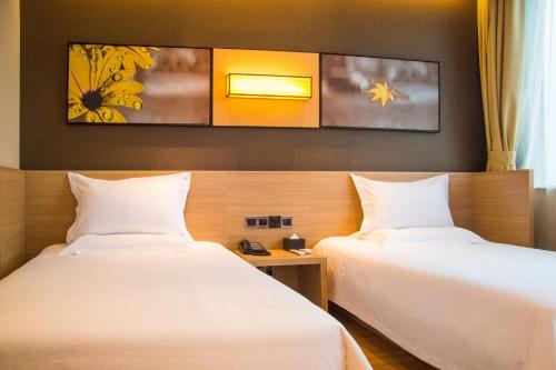 two beds in a hotel room with white sheets at IU Hotel Shijiazhuang Southwest Gaojiao District Hongqi Street in Shijiazhuang