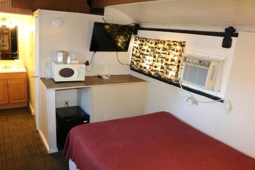 a small room with a bed and a microwave at Red Caboose Motel & Restaurant in Ronks