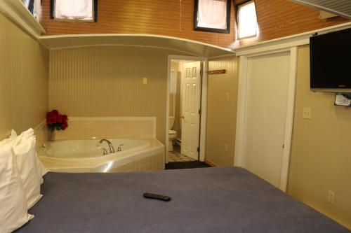 a bathroom with a tub and a bed with a tv at Red Caboose Motel & Restaurant in Ronks